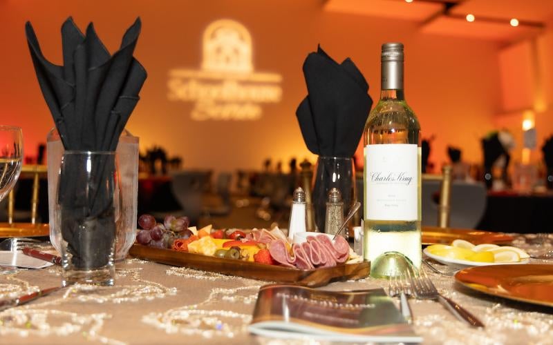 Table set with wine and charcuterie board with a Schoolhouse Soiree sign displayed in the background.